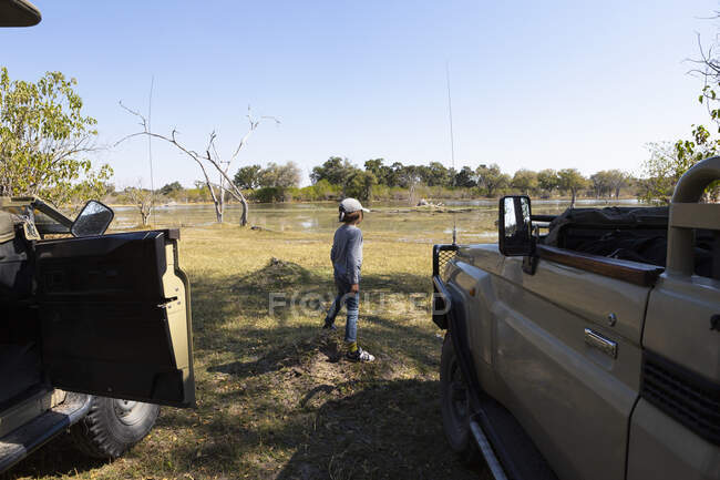 Un ragazzo che allunga le gambe con una jeep safari in una riserva naturale — Foto stock