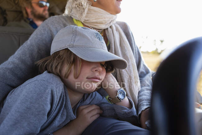 Eight year old boy in safari vehicle, sleeping beside his mother, in a safari jeep — Stock Photo