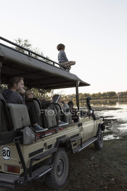 Menino de oito anos em cima de um veículo de safári com passageiros — Fotografia de Stock