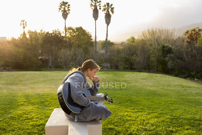 Teenage girl playing guitar and singing outdoors — Stock Photo