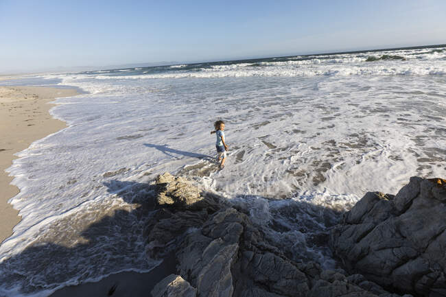 Jeune garçon jouant en surf sur une plage de sable fin — Photo de stock