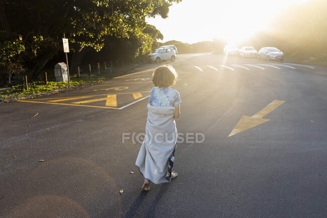 Boy wearing a beach towel going home at the end of a day on the beach. — Stock Photo