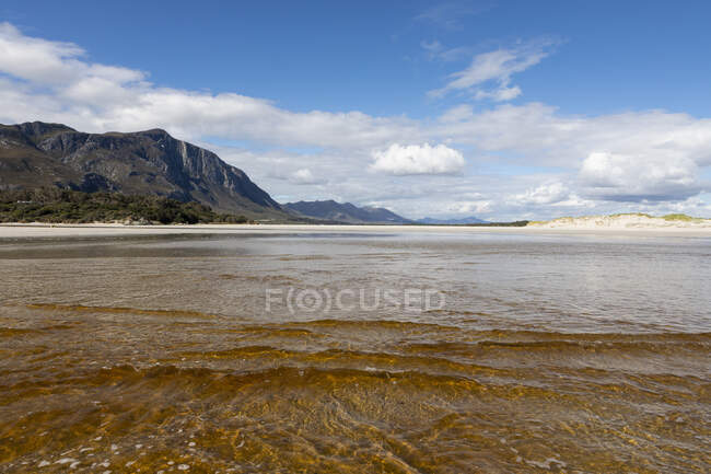 Uma ampla praia de areia, águas rasas, vista sobre a costa. — Fotografia de Stock