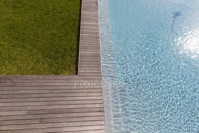 Vista aerea di una piscina con un bordo di coperta e piante in un giardino. — Foto stock