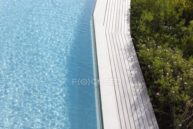 Vista aérea de uma piscina com uma borda pavimentada e plantas em um jardim. — Fotografia de Stock