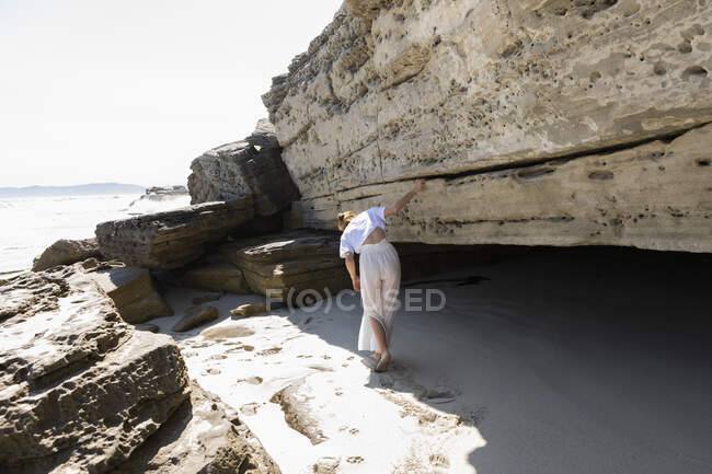 Adolescente explorando as falésias e estratos de rocha em uma praia na costa atlântica. — Fotografia de Stock