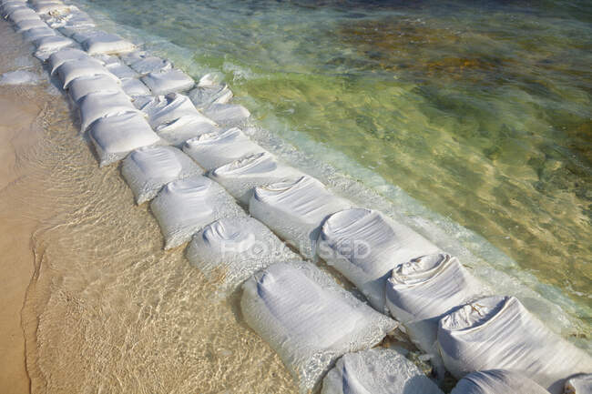 Sandbags in rows at the water's edge to prevent erosion of the beach — Foto stock