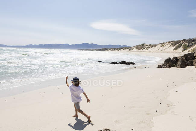 Otto anni ragazzo esplorare una spiaggia di sabbia. — Foto stock