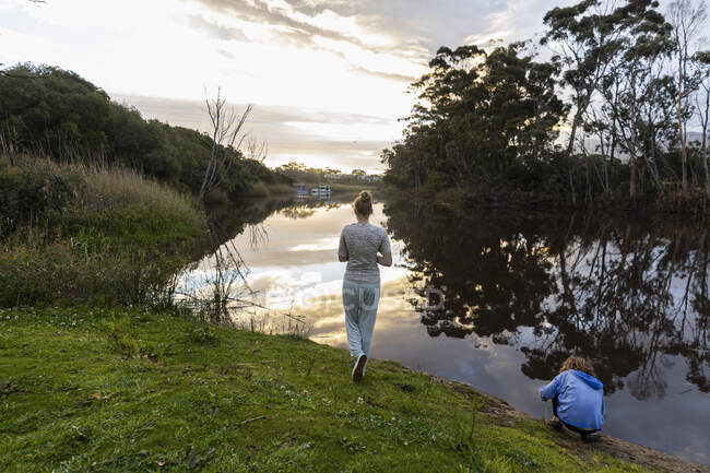 Adolescente et son jeune frère de huit ans près d'une rivière au coucher du soleil. — Photo de stock