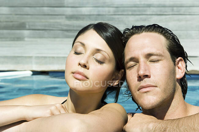 Чоловік і жінка в басейні насолоджуються сонцем, очі закриті . — стокове фото