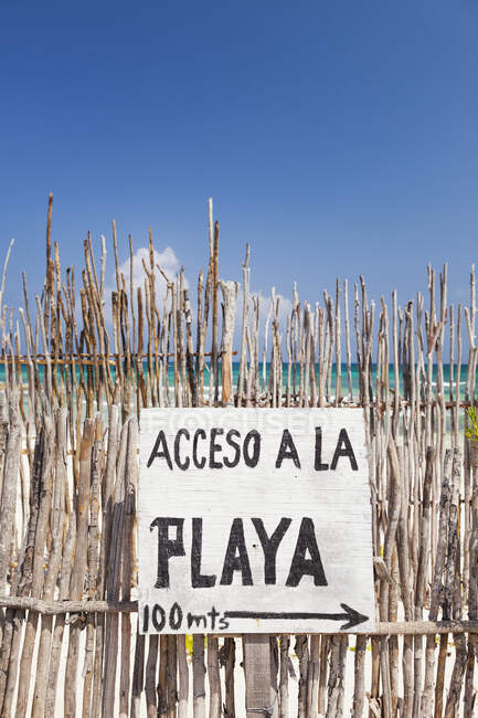 Beach access sign in Spanish,on a fence by the beach — Stockfoto