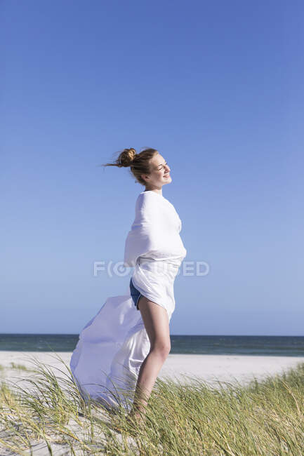Adolescente envuelta en blanco, Grotto Beach, Hermanus, Western Cape, Sudáfrica. - foto de stock