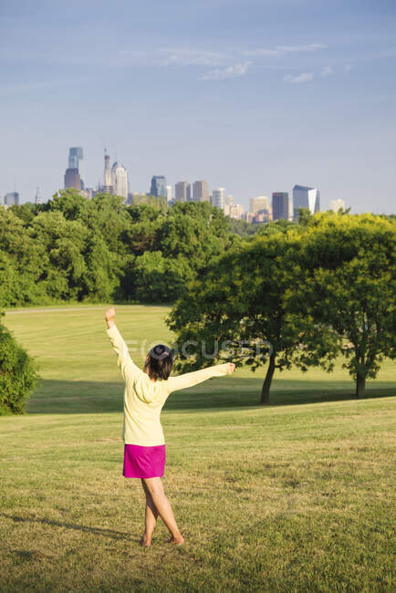Девушка танцует в парке перед горизонтом города. — стоковое фото