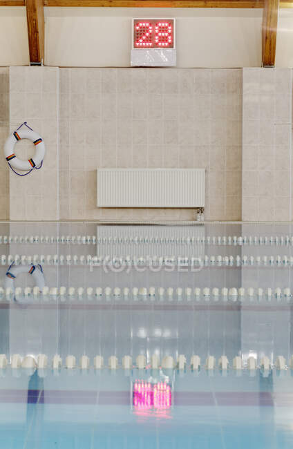 Indoor heated swimming pool, lifering and wall thermometer display, pink float in the water — Stock Photo