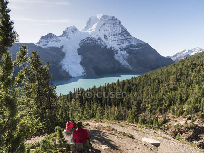 Dos personas descansando por una ruta de senderismo, vista del Monte Robson y las Rocosas. - foto de stock