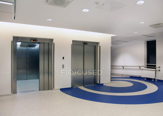 Elevators in the atrium of a new modern hospital, blue patterns on the floor — Stock Photo
