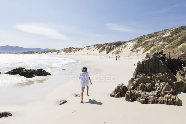 Eight year old boy exploring a wide sandy beach. — Stock Photo