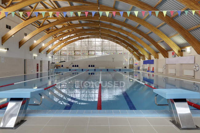 Indoor swimming pool, starting block, diving block and marked lanes, flat calm water — Stockfoto
