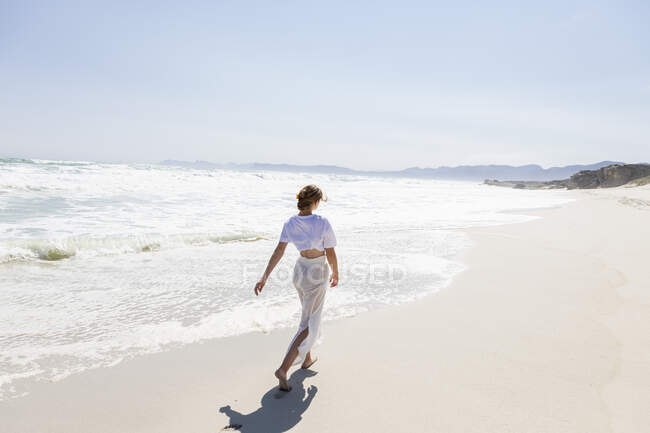 Adolescente marchant sur une plage de sable au bord de l'eau — Photo de stock