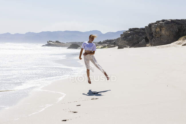 Девочка-подросток танцует одна на песчаном пляже в Южной Африке у воды — стоковое фото