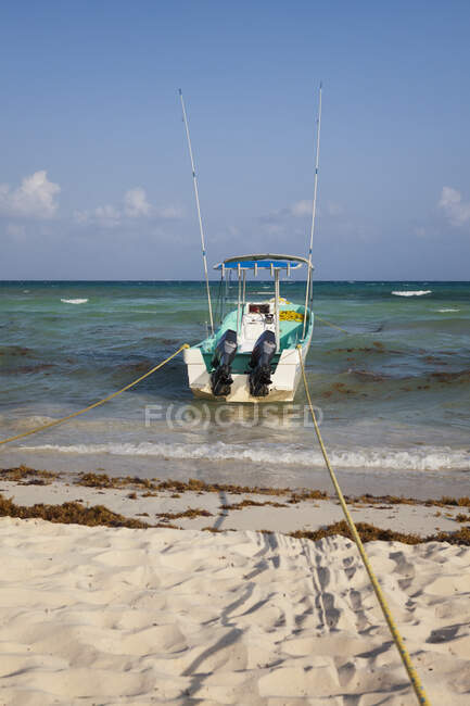 Un barco pesquero anclado en el borde del agua, en la playa - foto de stock
