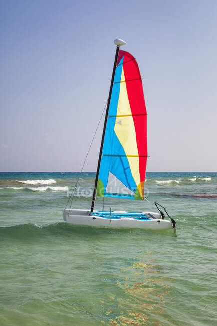 Un catamarano in acque poco profonde con la vela alzata. — Foto stock