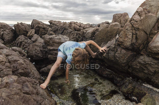 Маленький мальчик, исследующий приливный бассейн, Де Келдерс, Западная Мыса, Южная Африка. — стоковое фото