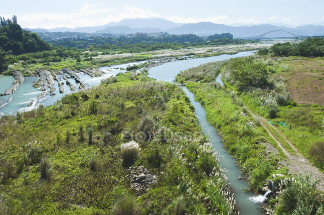 Canales de riego y una zanja de desbordamiento de drenaje cortados en el paisaje por un río. - foto de stock