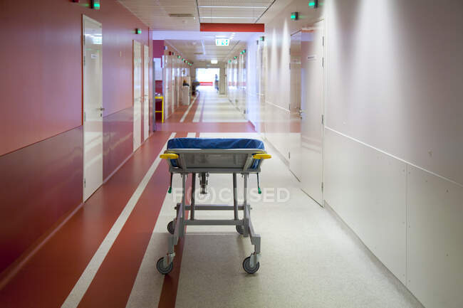 Corridor and waiting areas of a modern hospital with seating, a trolley bed wih blue mattress — Stock Photo