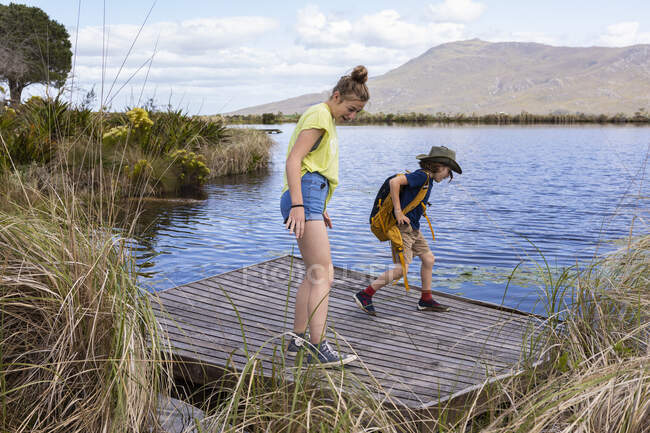 Adolescente y hermano menor explorando estanque, Stanford Valley Guest Farm, Stanford, Western Cape, Sudáfrica. - foto de stock