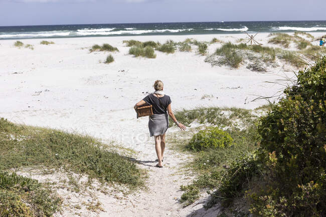 Взрослая женщина с корзиной для пикника на пляже Гротто, Херманус, Западная Мыса, Южная Африка. — стоковое фото