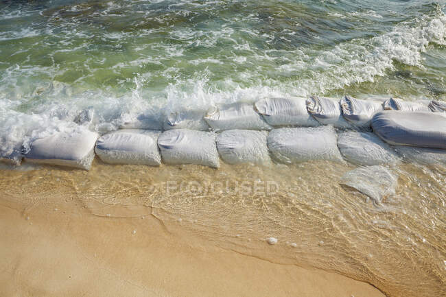 Sandbags in rows at the water's edge to prevent erosion of the beach — Stock Photo