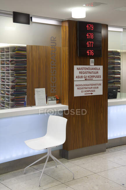 Waiting area and reception desk at a modern hospital, with signs and electronic display — Stock Photo