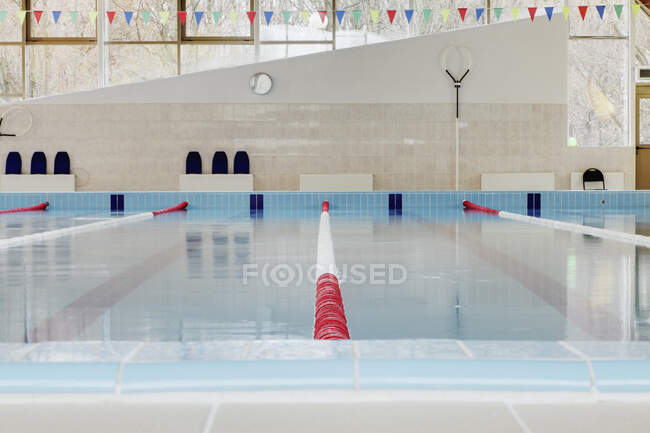 Indoor swimming pool, red and white dividers in swim lanes, surface view. — Stock Photo