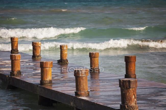 A wooden pier with posts or bollards on the coastline — Foto stock