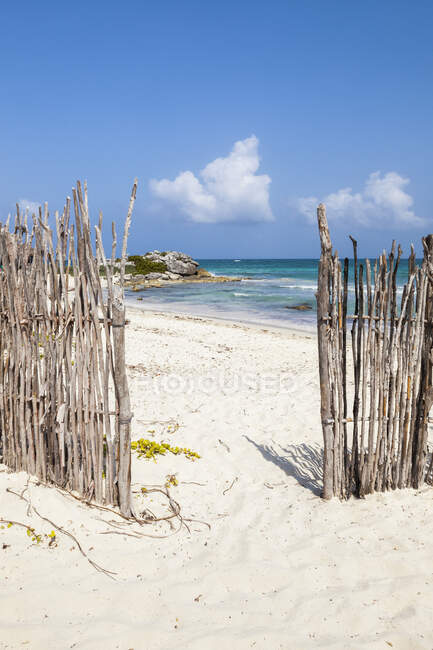 Une ouverture dans la clôture sur une plage de sable blanc — Photo de stock