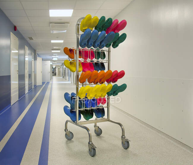 Corridor and waiting areas of a modern hospital, a rack with colourful surgical clogs. — Stock Photo