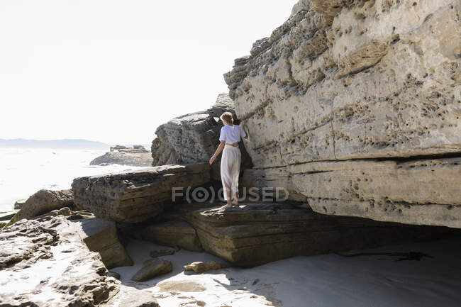 Adolescente explorando los acantilados y estratos rocosos en una playa en la orilla del Atlántico. - foto de stock