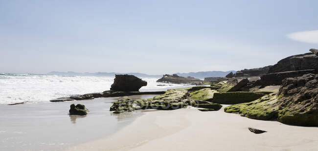 Formaciones rocosas en una playa de arena en una reserva natural en la costa del Océano Atlántico. - foto de stock