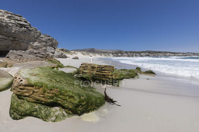 Скельні утворення та скелі з видом на піщаний пляж з хвилями, що ламаються на березі — стокове фото