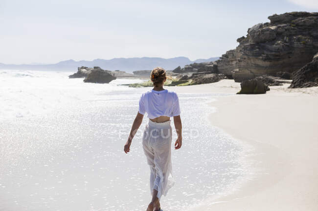 Ragazza adolescente che cammina su una spiaggia sabbiosa sul bordo dell'acqua — Foto stock