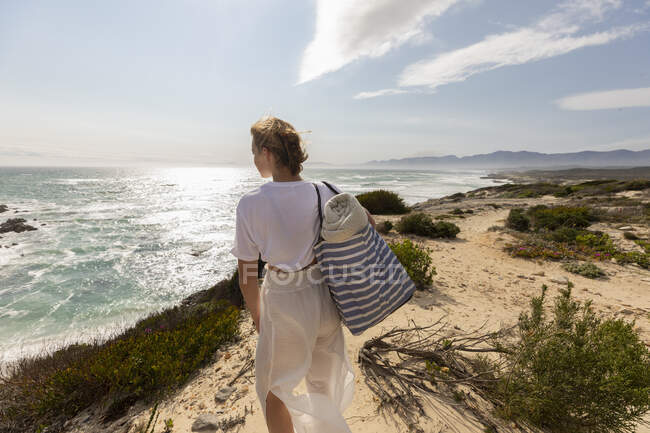 Adolescente de pé no topo de um penhasco olhando sobre a costa e entrada. — Fotografia de Stock
