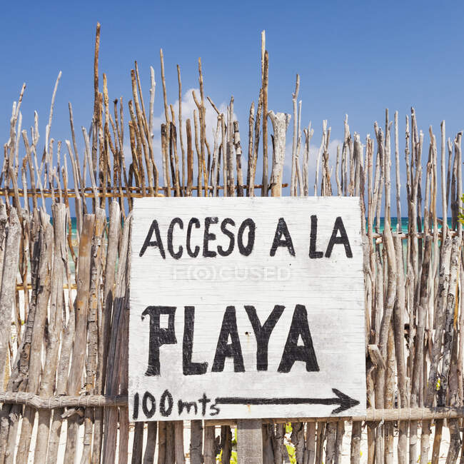 Sinal de acesso à praia em espanhol, numa cerca junto à praia — Fotografia de Stock