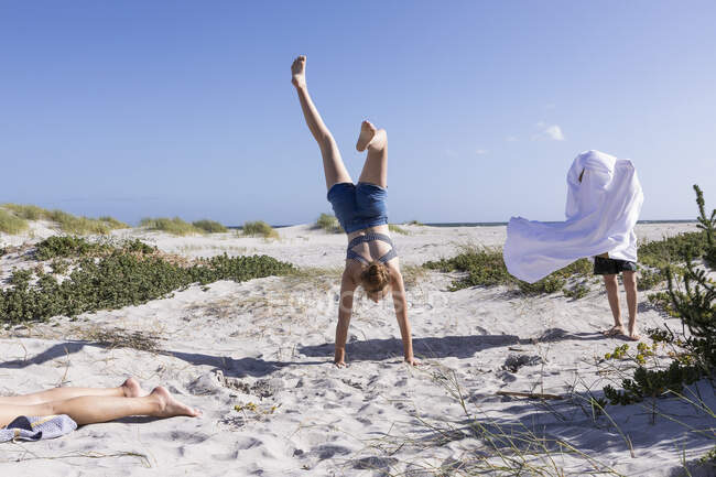 Teenage girl doing hand stand, Grotto Beach, Hermanus, Western Cape, South Africa. — Stock Photo