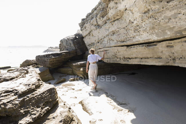 Teenage girl exploring the cliffs and rock strata on a beach on the Atlantic shore. — Stock Photo