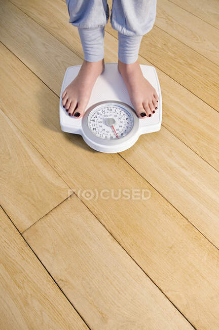 Woman standing on weighing scale, feet and lower legs. — Stock Photo