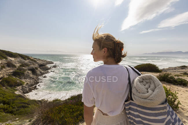 Adolescente de pé no topo de um penhasco olhando sobre a costa e entrada. — Fotografia de Stock