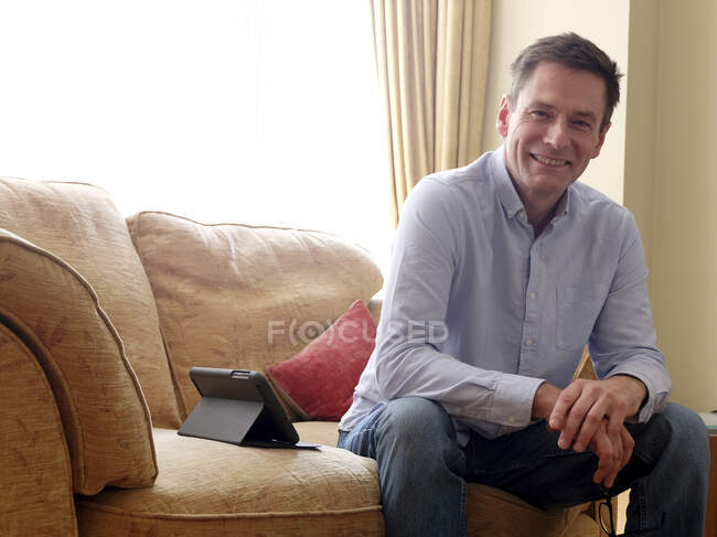 Homem sentado no sofá sorrindo para a câmera. — Fotografia de Stock