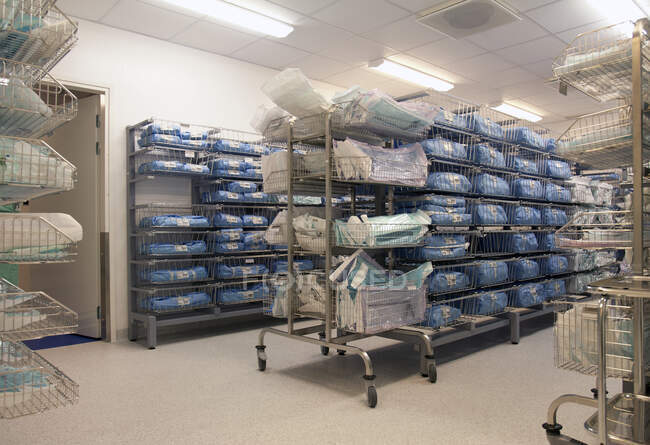 Storage room in a modern hospital, rows of sterile equipment packs in blue fabric. — Stock Photo
