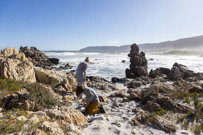Dos niños explorando las rocas irregulares y la costa atlántica. - foto de stock